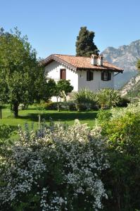 een wit huis met bomen en bloemen ervoor bij Laghel7 Agritur in Arco