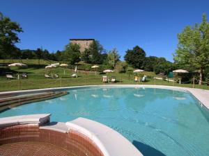 una gran piscina con sillas y sombrillas en Belvilla by OYO Casa Ginepro, en Apecchio