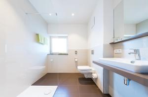 a white bathroom with a sink and a toilet at Hotel Die Alm in Oberkirch