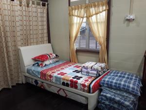 um pequeno quarto com uma cama e uma janela em Teratak Opah Kamunting em Taiping