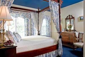 a bedroom with a canopy bed and a window at A Williamsburg White House Inn in Williamsburg