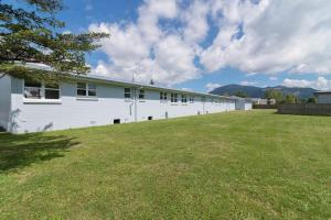 a large white building with a large grass yard at Cleveland Thermal Motel in Rotorua