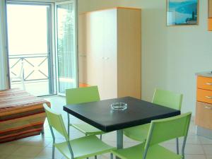 une salle à manger avec une table noire et des chaises vertes dans l'établissement Apartment in a residence on Lake Maggiore near the beach, à Verbania