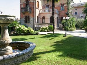 a large building with a fountain in front of a yard at Belvilla by OYO Villa Melina in Desenzano del Garda