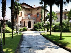 a house with palm trees in front of a walkway at Belvilla by OYO Villa Melina in Desenzano del Garda