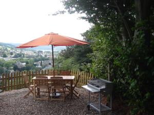 a table and chairs with an umbrella and a grill at Detached house with breathtaking views in Malmedy