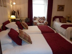 a hotel room with two beds and a chair at Comelybank Guesthouse in Crieff