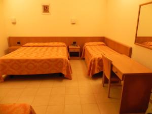 a hotel room with two beds and a desk at Hotel Il Saraceno in Volastra