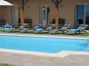 eine Gruppe Stühle und ein Pool in der Unterkunft Luxury villa with pool in Thermes Magnoac in Thermes-Magnoac