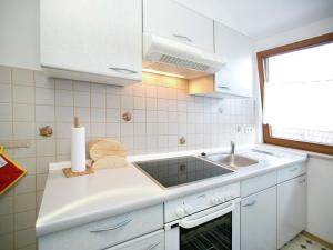 cocina con armarios blancos, fregadero y ventana en Spacious apartment near Lake Constance, en Ahausen