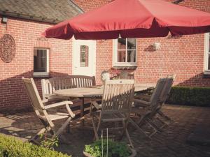 a wooden table and chairs with a red umbrella at Spacious Villa in Neerpelt near Welvaart Marina in Neerpelt