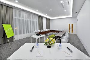 una sala conferenze con tavoli e sedie bianchi e schermo di Whiz Prime Hotel Sudirman Cilacap a Cilacap