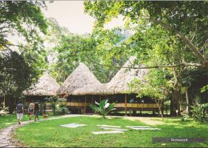 people walking in front of a building with grass roofs at The Barefoot At Havelock in Havelock Island