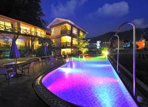 Ci Meng Rou Resort Villa في داهو: حمام سباحة مع أضواء ملونة أمام المبنى