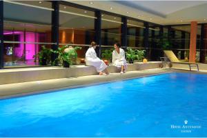 two women are sitting next to a swimming pool at Hotel Antunovic Zagreb in Zagreb