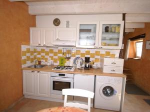 Fresse-sur-MoselleにあるCosy holiday home with gardenの白いキャビネット、シンク、食器洗い機付きのキッチンが備わります。
