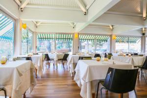 a dining room with white tables and chairs and windows at Hotel Augustus in Fano