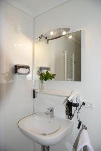 a white bathroom with a sink and a mirror at Naturparkhotel & Landgasthof Stromberg in Sachsenheim