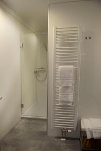 a white bathroom with a shower and towels at Naturparkhotel & Landgasthof Stromberg in Sachsenheim