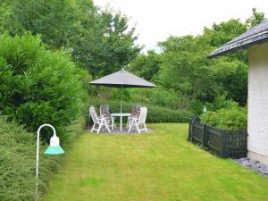 een tafel met stoelen en een parasol in een tuin bij Ferienwohnung in der Nähe des Skigebietes in Willingen