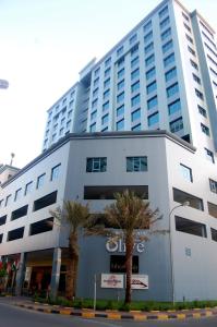 a large white building with palm trees in front of it at The Olive Hotel, Juffair in Manama
