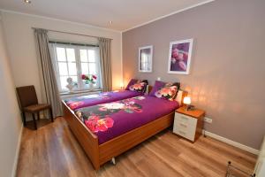 una camera da letto con un letto con lenzuola viola e una finestra di Ferienhaus Burgblick Brueggen a Brüggen