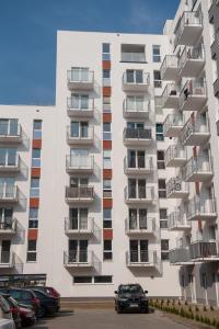 波茲南的住宿－Apartament Winogrady Hawelańska，带阳台的公寓楼,停车场内有车辆停放