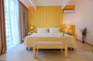 - une chambre avec un grand lit et un mur jaune dans l'établissement Phoenicia Luxury Hotel, à Mamaia Nord – Năvodari