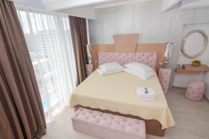 ママイア・ノルドにあるPhoenicia Luxury Hotelのピンクベッド1台(鏡付)が備わるベッドルーム1室を提供しています。