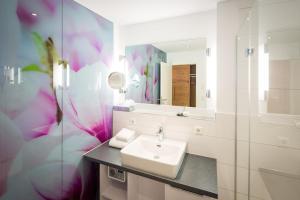 a white bathroom with a sink and a mirror at Hotel Alte Schule in Lindau