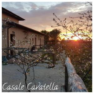 a sunset over a house with a tree and a fence at Casale Cavatella in Sermoneta