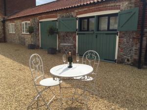 ein Tisch und zwei Stühle mit einer Flasche Wein drauf in der Unterkunft Hill Farm Bed and Breakfast in Little Massingham