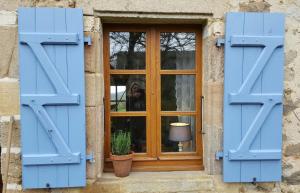 a window with blue shutters and a person taking a picture at Domaine Charente - Cottage Charente in Mazières