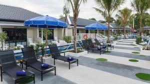 uma piscina com cadeiras e guarda-sóis azuis num resort em Tuana Hotels Brook Pool Access em Chalong