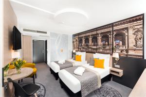 ブダペストにあるメルキュール ブダペスト シティ センターのベッド2台とデスクが備わるホテルルームです。