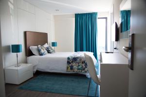 Pokój hotelowy z łóżkiem z niebieskimi zasłonami w obiekcie Tomas Guest House II w mieście Covilhã