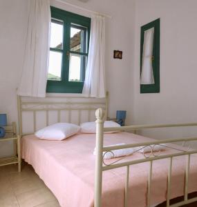 KorissiaにあるAnastasia Apartmentsのベッドルーム1室(ピンクのシーツが敷かれたベッド1台、窓付)