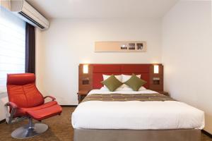ein Schlafzimmer mit einem Bett und einem roten Stuhl in der Unterkunft HOTEL MYSTAYS Haneda in Tokio