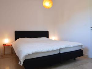 a bedroom with a white bed with a black headboard at Modern villa with private pool in Malauc n in Malaucène