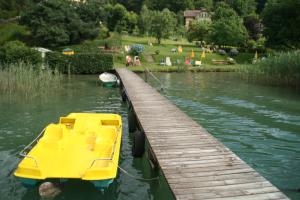 ein gelbes Boot, das neben einem Dock im Wasser parkt in der Unterkunft Pension Seevilla Annelies in Maria Wörth