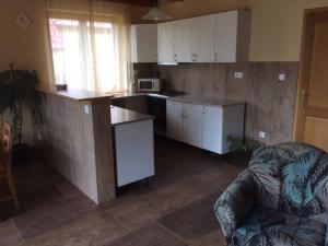 a kitchen with white cabinets and a couch in a room at Sóstó Gold Vendégház in Nyíregyháza