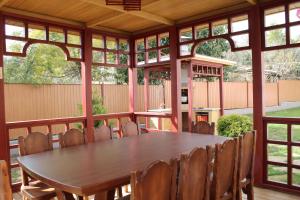 a screened in porch with a wooden table and chairs at Tihaya Gavan in Adler