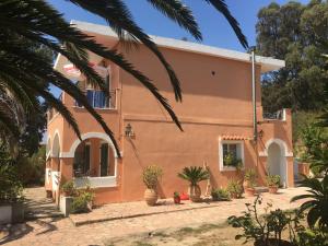 ein Haus mit einer Palme davor in der Unterkunft Floros Apartments in Agios Stefanos