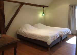 - une chambre avec un lit avec des draps blancs et une table dans l'établissement Fietsboerderij, à Sinderen
