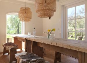 una gran mesa de madera en una habitación con ventanas en Fietsboerderij, en Sinderen