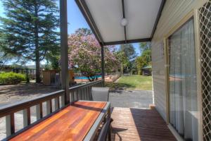 a deck with a wooden bench on a house at BIG4 Twin Dolphins Holiday Park in Tuncurry