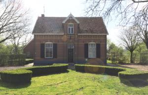 une maison en briques rouges avec des buissons devant elle dans l'établissement Fietsboerderij, à Sinderen