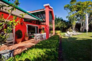タコロンテにあるLuxury Villa Golf Tenerifeの赤い家(椅子付)とパティオ