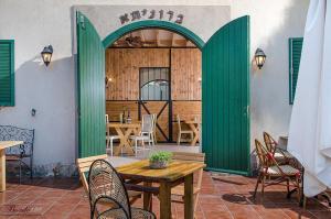 a patio with a table and chairs and a green door at Zimer Baronita in Zikhron Ya'akov