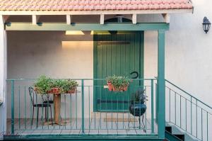 ein Balkon mit zwei Stühlen und eine grüne Tür mit zwei Pflanzen in der Unterkunft Zimer Baronita in Zichron Ja’akow